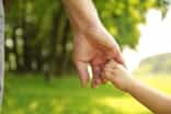 a close-up of a parent walking hand in hand with child